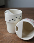 Two ceramic containers with heart patterns on a wooden surface