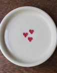 White ceramic plate with red heart designs on a wooden surface