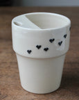 White ceramic cup with black heart designs on a wooden surface