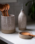 Speckled ceramic containers with wooden spoons on a kitchen counter