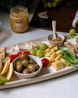 Platter of assorted cheeses, crackers, and fruits with a jar of mustard on a table.