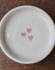 White ceramic plate with pink heart designs on a wooden surface