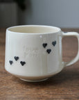White mug with 'love you' text and heart shapes on a wooden surface