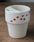 White ceramic cup with red heart designs on a wooden surface