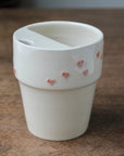 White ceramic cup with pink heart designs on a wooden surface