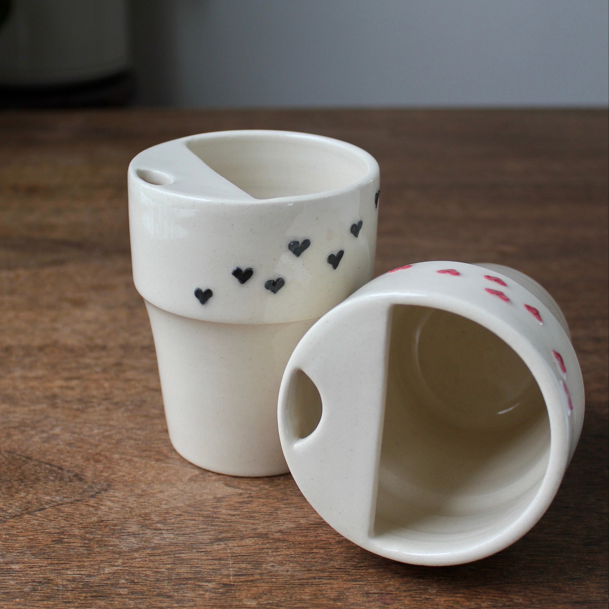 Two ceramic containers with heart patterns on a wooden surface