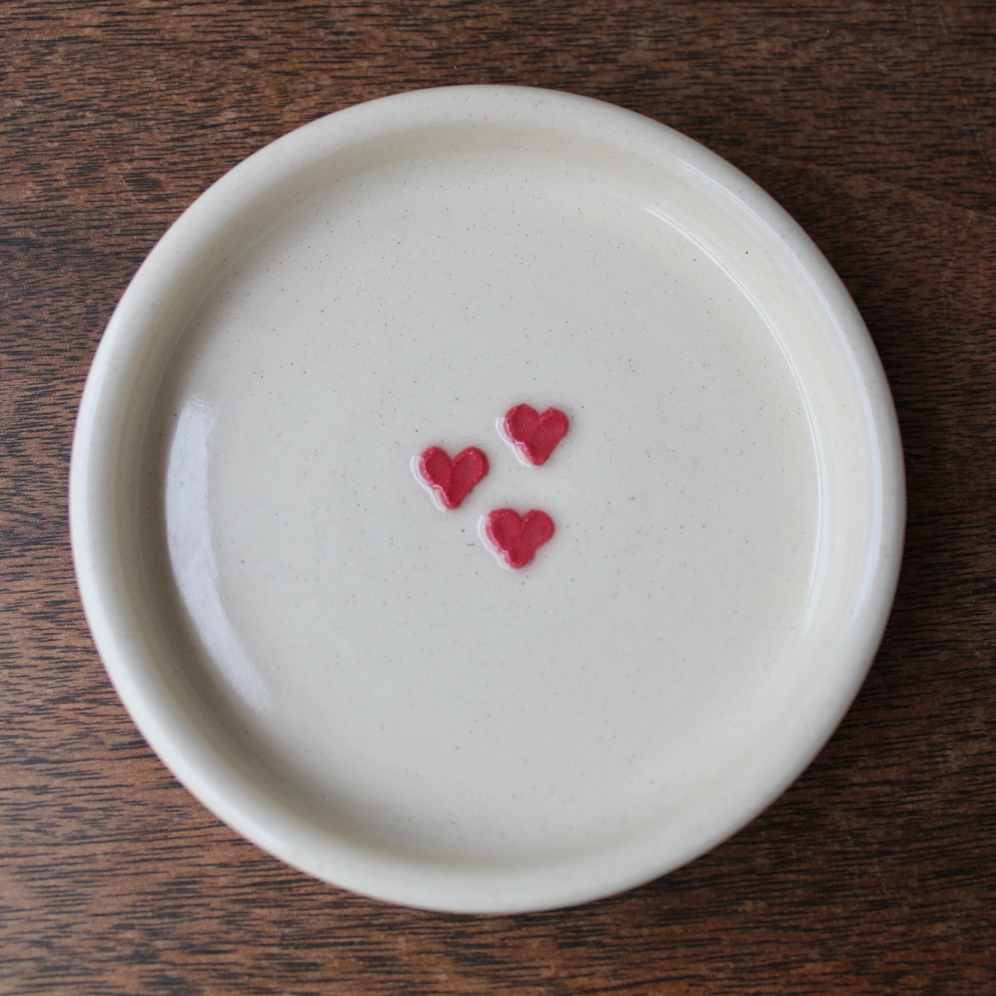 White ceramic plate with red heart designs on a wooden surface