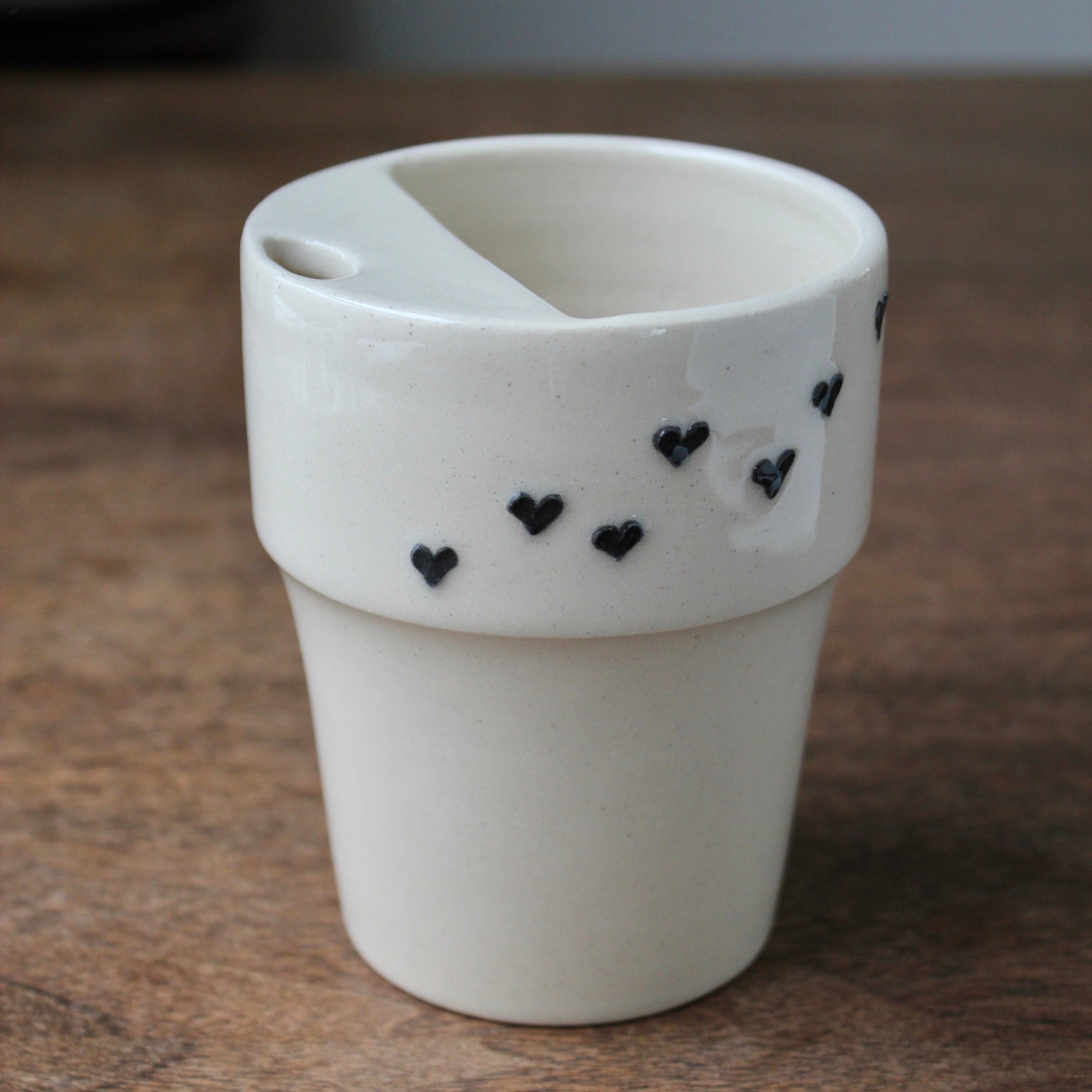White ceramic cup with black heart designs on a wooden surface
