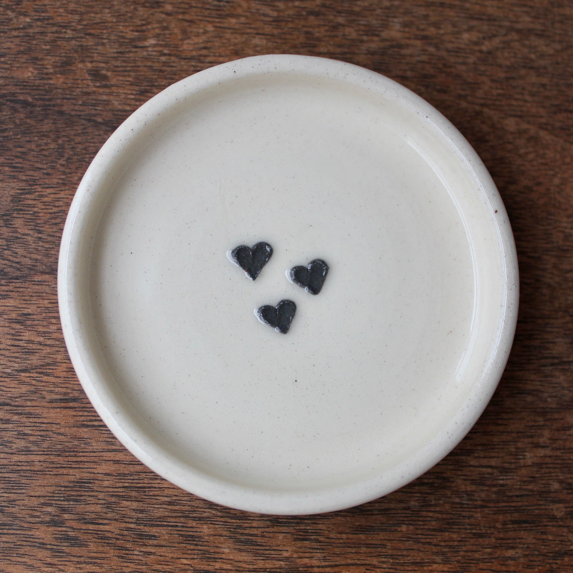 White ceramic plate with three black heart shapes on a wooden surface