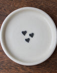 White ceramic plate with three black heart shapes on a wooden surface