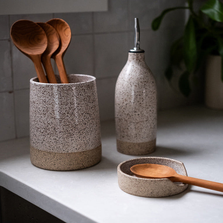Speckled ceramic containers with wooden spoons on a kitchen counter