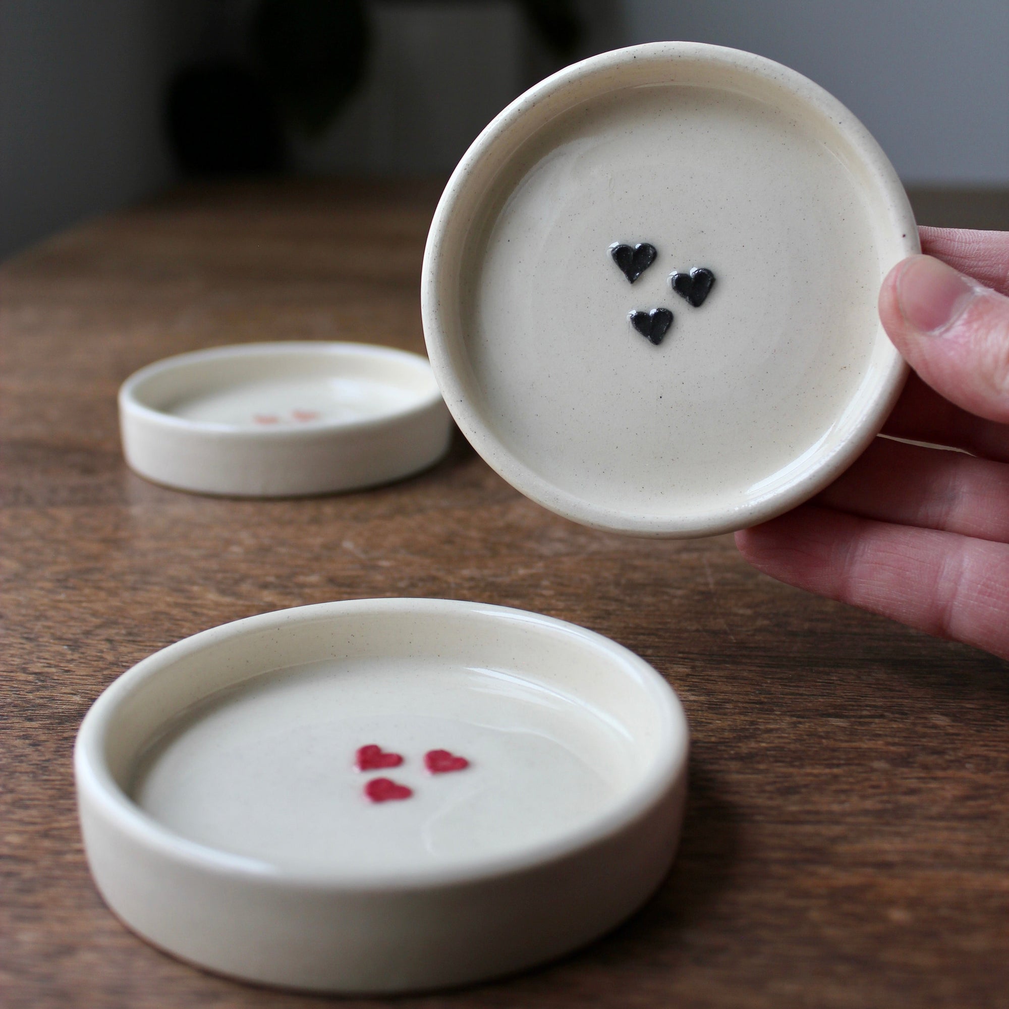 Three ceramic dishes with heart designs on a wooden surface