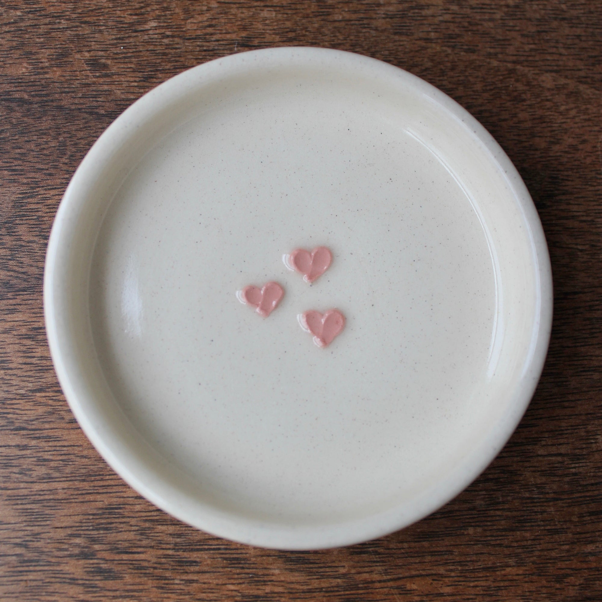 White ceramic plate with pink heart designs on a wooden surface