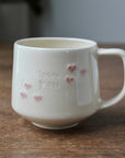 White ceramic mug with 'I love you' and heart designs on a wooden surface