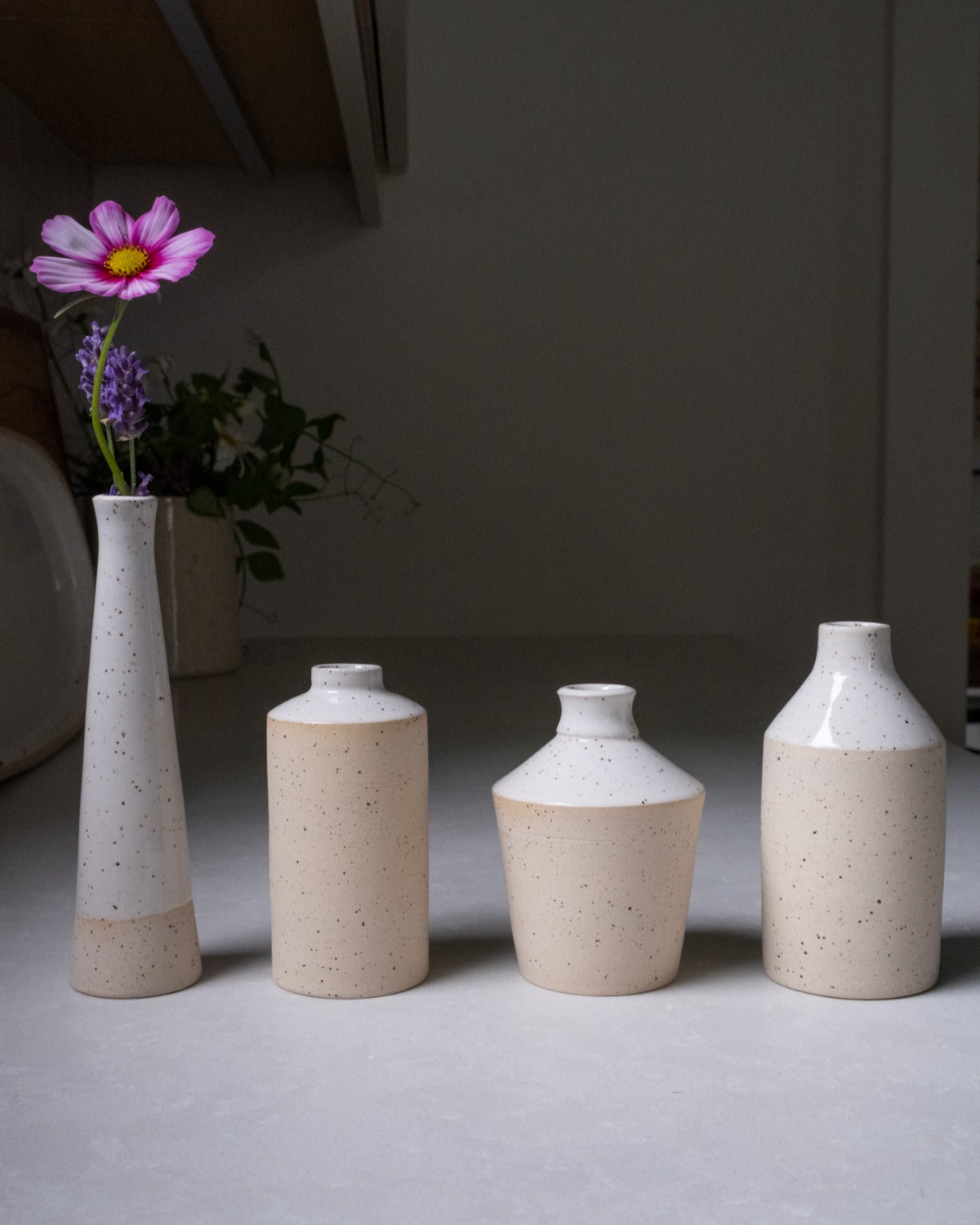 Set of four ceramic vases on a neutral surface with a blurred background