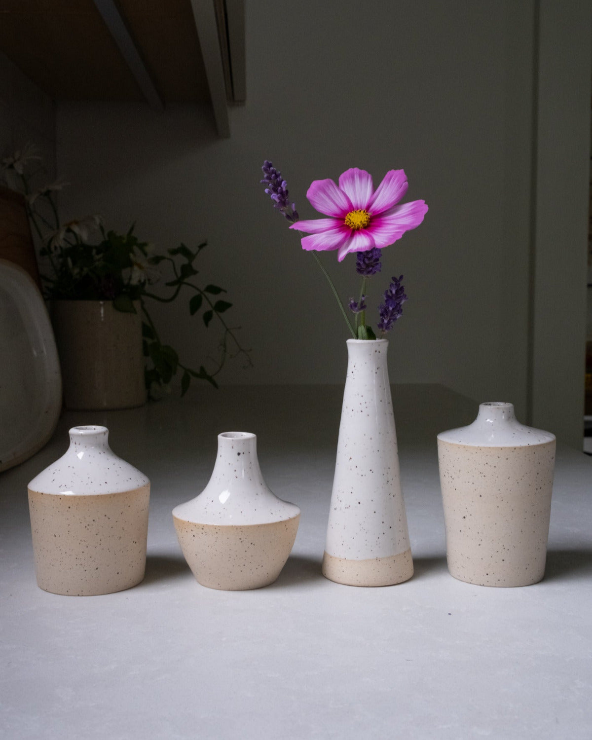 Set of ceramic vases with a single pink flower on a neutral background