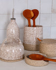 Speckled kitchen ceramic containers with wooden spoons on a tiled wall background